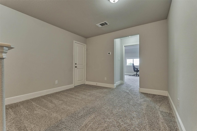 spare room with visible vents, carpet, baseboards, and a textured ceiling