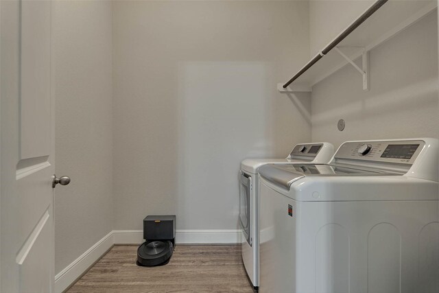 clothes washing area featuring laundry area, washing machine and dryer, light wood-style flooring, and baseboards