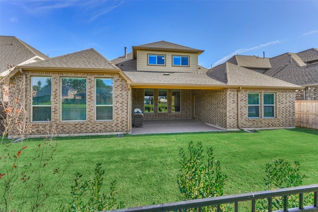 back of property with a patio area, a shingled roof, a yard, and fence