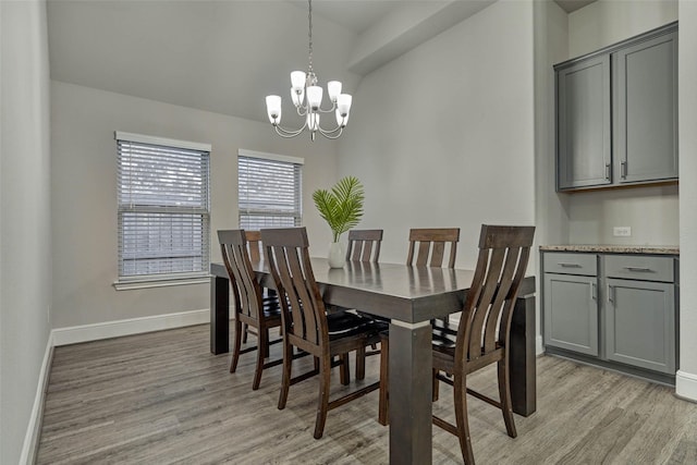 dining space with lofted ceiling, baseboards, light wood-style floors, and an inviting chandelier