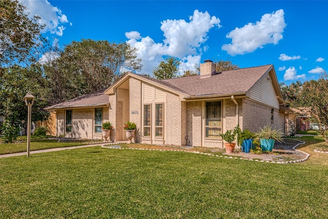 mid-century home with a front yard, brick siding, roof with shingles, and a chimney