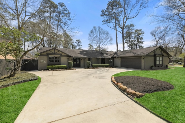 mid-century modern home featuring a front yard, an attached garage, fence, and driveway