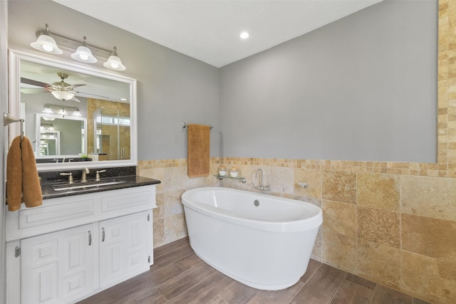 full bathroom with vanity, a ceiling fan, wood tiled floor, a soaking tub, and tile walls