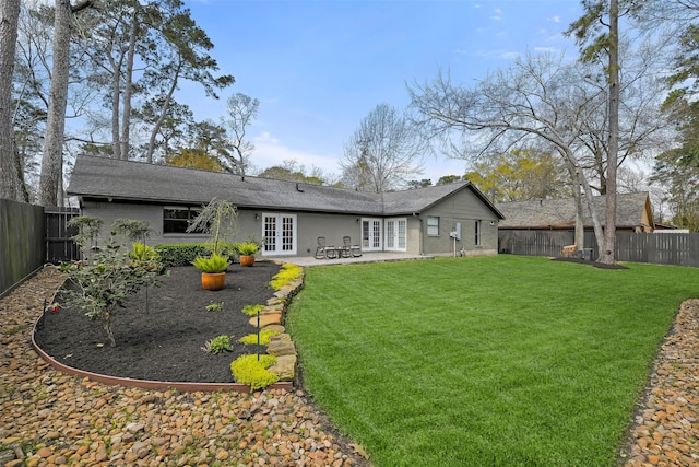 back of house with french doors, a lawn, a fenced backyard, and brick siding