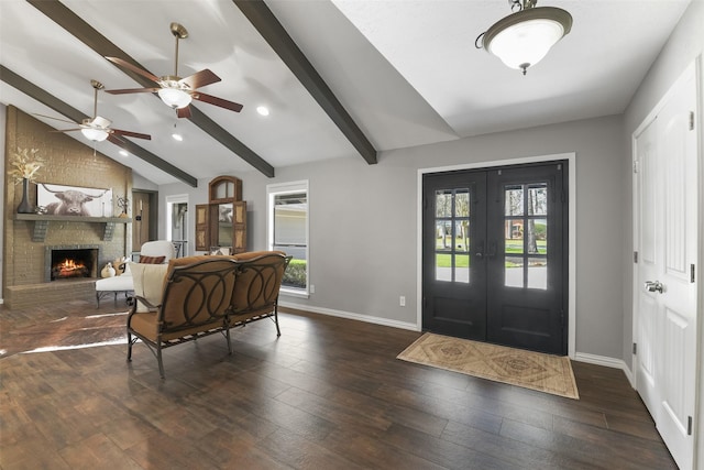 foyer entrance featuring lofted ceiling with beams, french doors, wood-type flooring, a fireplace, and baseboards