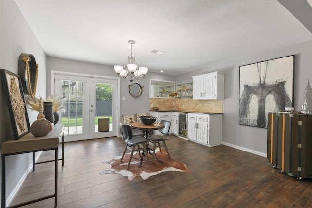 dining space featuring beverage cooler, visible vents, dark wood finished floors, french doors, and a chandelier