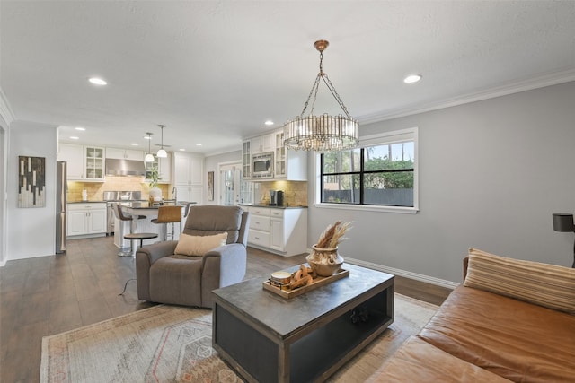 living area featuring a notable chandelier, dark wood-style flooring, recessed lighting, and ornamental molding