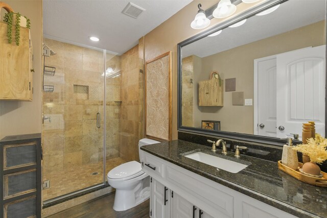 bathroom with vanity, wood finished floors, visible vents, a stall shower, and toilet