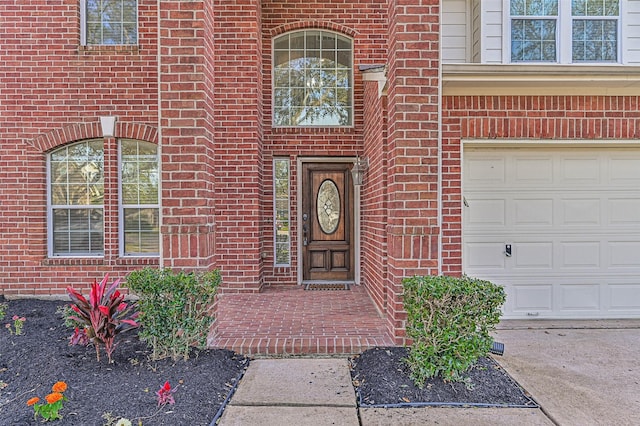 property entrance with an attached garage and brick siding