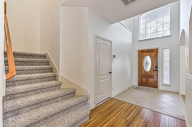 entrance foyer with tile patterned floors, stairway, visible vents, and a wealth of natural light