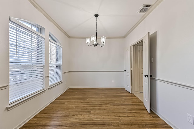 unfurnished dining area with a notable chandelier, visible vents, crown molding, and wood finished floors