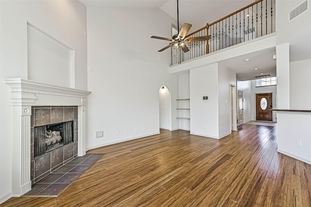 unfurnished living room with visible vents, a ceiling fan, wood finished floors, a fireplace, and baseboards