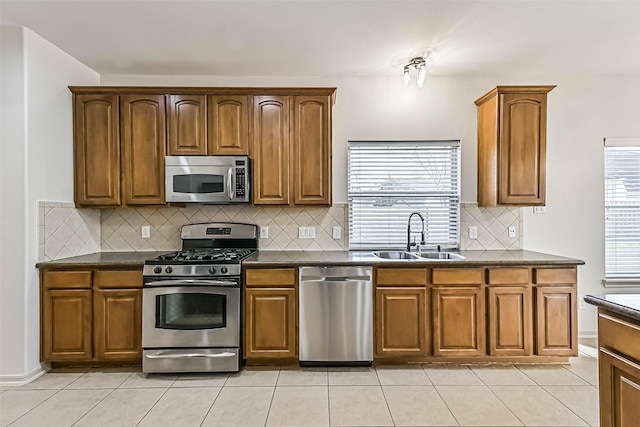 kitchen featuring dark countertops, light tile patterned flooring, appliances with stainless steel finishes, and a sink