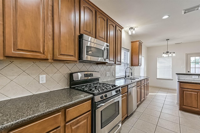 kitchen featuring visible vents, a sink, dark stone countertops, appliances with stainless steel finishes, and light tile patterned floors