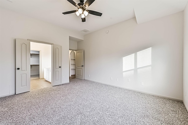 unfurnished bedroom featuring a ceiling fan, a spacious closet, carpet, and baseboards