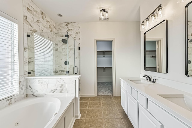 bathroom featuring a tub with jets, a shower stall, a healthy amount of sunlight, and a sink