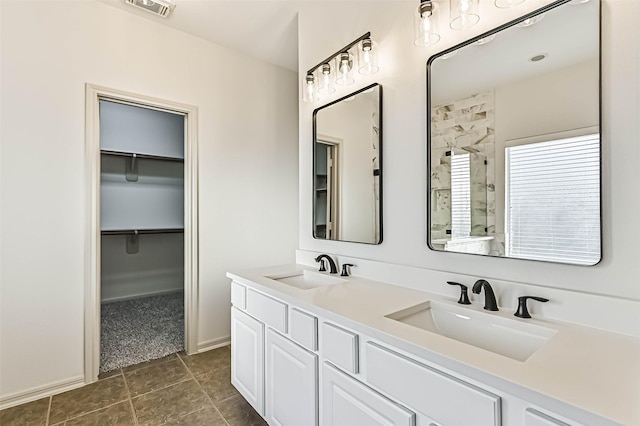 full bath with visible vents, a shower stall, a walk in closet, and a sink