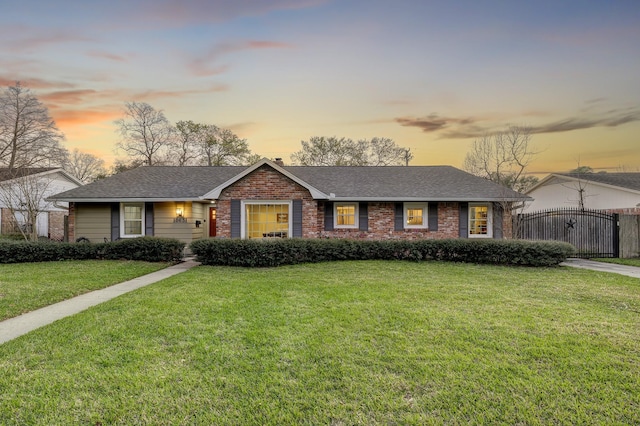 single story home featuring a front lawn, a gate, brick siding, and a shingled roof