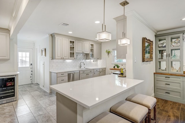 kitchen featuring visible vents, dishwasher, light countertops, ornamental molding, and a sink