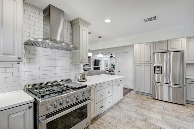 kitchen featuring visible vents, light countertops, decorative backsplash, stainless steel appliances, and wall chimney exhaust hood