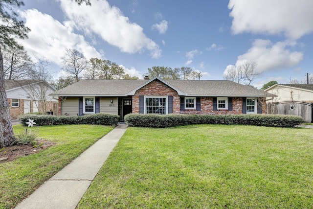 ranch-style house featuring brick siding, a shingled roof, a front yard, and fence