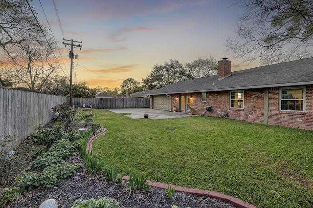 view of yard featuring a garage, a fenced backyard, concrete driveway, and a patio area