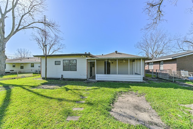 rear view of house featuring a yard, fence, and a sunroom