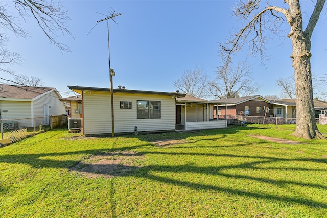 back of house with central air condition unit, a lawn, and fence