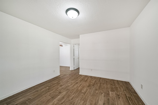 empty room featuring baseboards, a textured ceiling, and dark wood-style flooring