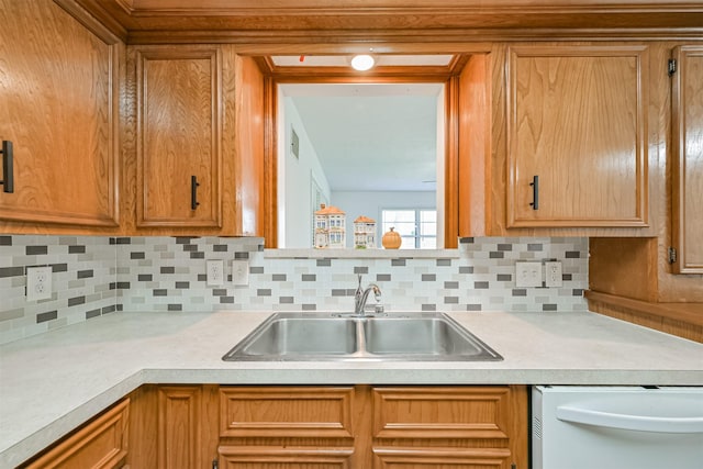 kitchen featuring a sink, light countertops, decorative backsplash, and white dishwasher