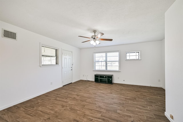 interior space with visible vents, baseboards, wood finished floors, a textured ceiling, and a ceiling fan