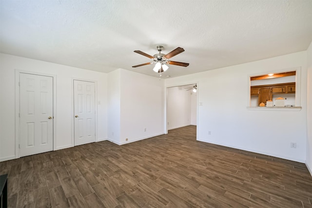 empty room with a textured ceiling, a ceiling fan, dark wood-style flooring, and baseboards