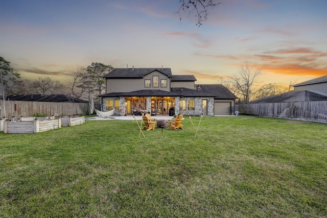 back of house at dusk featuring a patio, fence, a vegetable garden, an attached garage, and a lawn