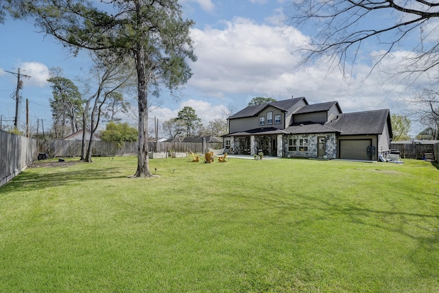 view of yard with driveway, a fenced backyard, and an attached garage