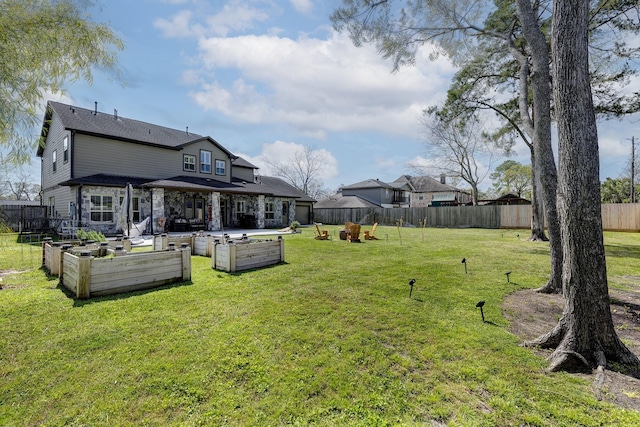 rear view of house with a garden, a yard, and a fenced backyard