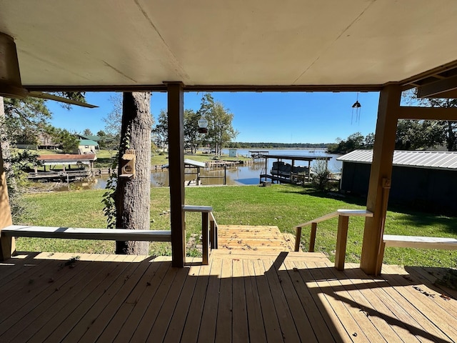 wooden terrace featuring boat lift, a water view, a lawn, and a boat dock