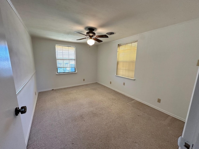 carpeted empty room with visible vents, baseboards, and a ceiling fan