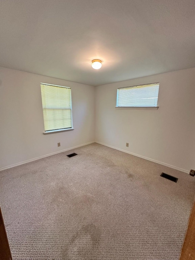 empty room featuring baseboards, visible vents, and carpet floors