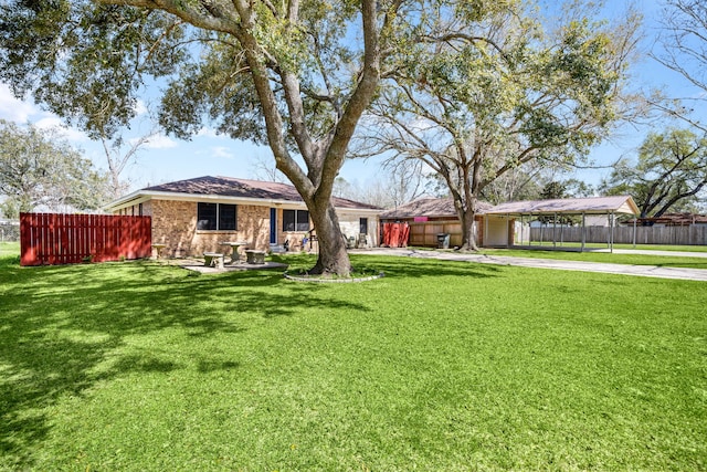 view of yard featuring a detached carport, fence, and driveway