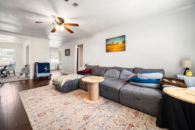 living area featuring visible vents, ceiling fan, ornamental molding, hardwood / wood-style floors, and a textured ceiling