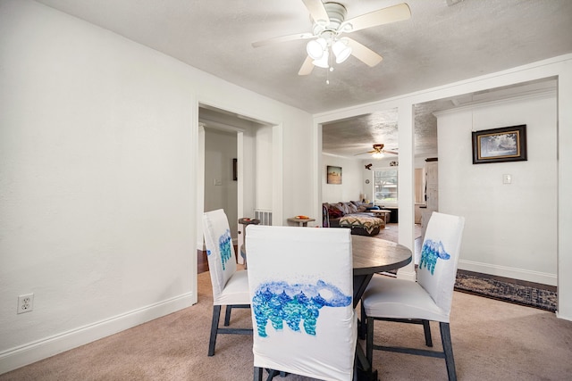 dining room featuring light colored carpet, a textured ceiling, baseboards, and ceiling fan