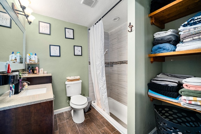 bathroom with visible vents, baseboards, wood finish floors, toilet, and a tile shower