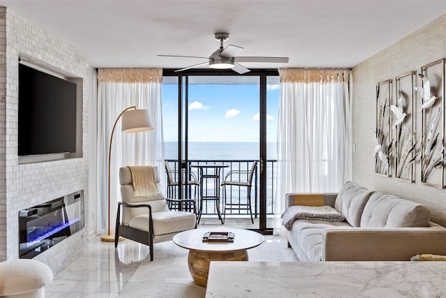 living room featuring expansive windows, a water view, a glass covered fireplace, and a ceiling fan