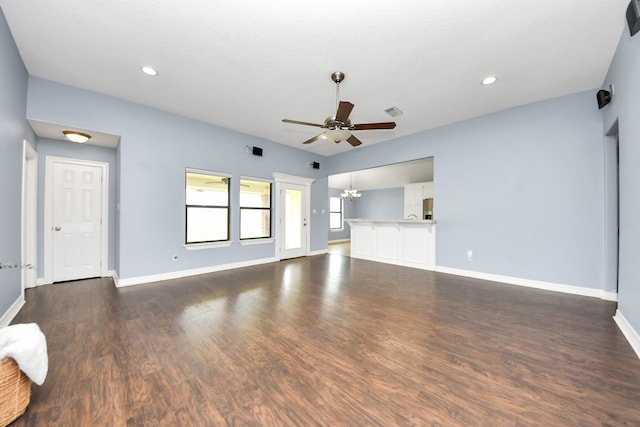 unfurnished living room featuring visible vents, baseboards, recessed lighting, ceiling fan with notable chandelier, and dark wood-style flooring