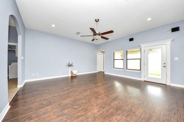 unfurnished living room featuring arched walkways, washer / dryer, wood finished floors, and a ceiling fan