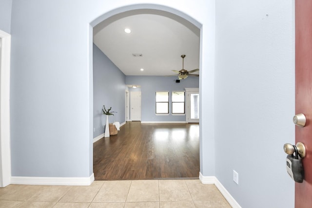 hallway with tile patterned flooring, recessed lighting, baseboards, and arched walkways