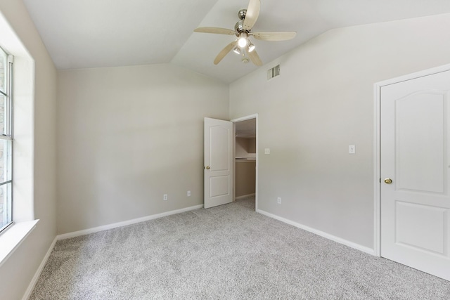 empty room featuring visible vents, baseboards, lofted ceiling, carpet floors, and a ceiling fan