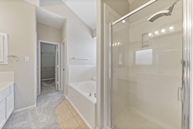 bathroom with vanity, tile patterned flooring, a shower stall, a walk in closet, and a bath