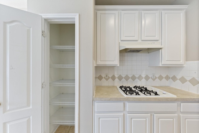 kitchen with white cabinetry, light countertops, and under cabinet range hood