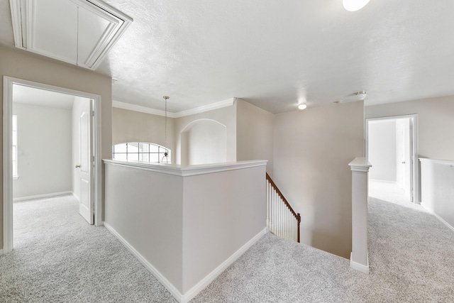 corridor featuring attic access, an upstairs landing, baseboards, and carpet floors